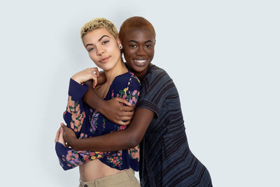 Portrait of smiling lesbian couple embracing against white background