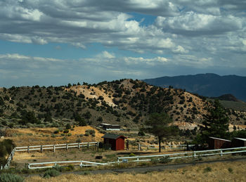 Scenic view of small red barn and field against sky and dramatic clouds