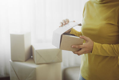 Midsection of woman holding paper in box at home
