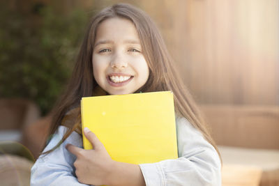 Portrait of smiling girl holding yellow indoors