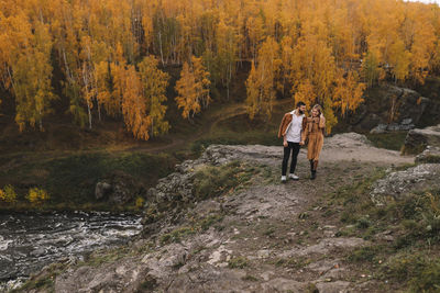 Happy people in love are travel hike in nature in the autumn forest. romantic trip to countryside