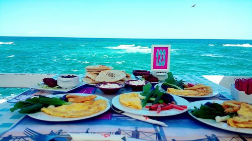 Close-up of food on table by sea against sky