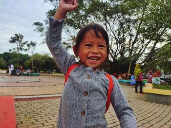 Portrait of happy girl against trees