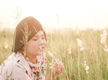 Close-up of woman looking at plants against clear sky