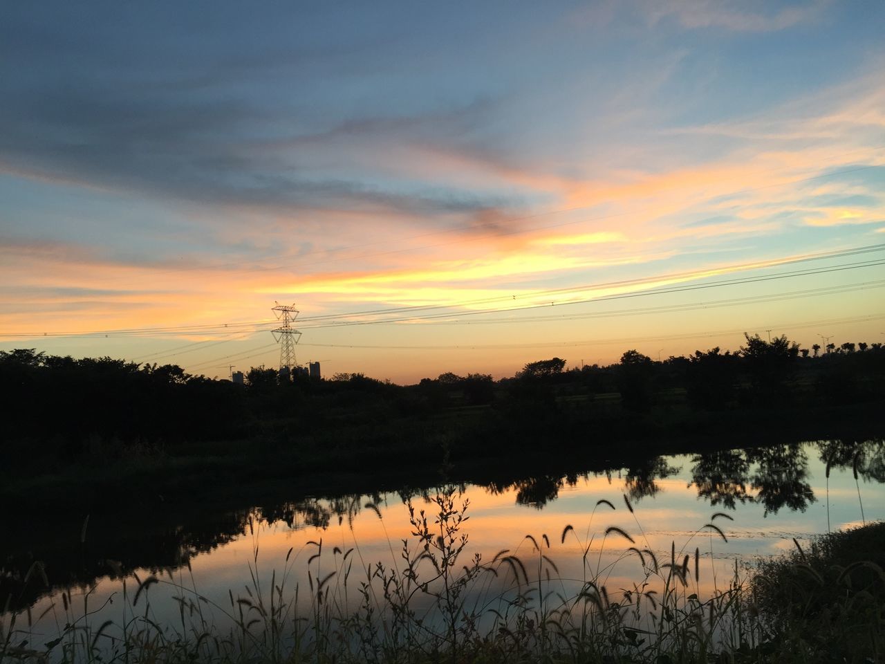 sunset, tranquility, tranquil scene, scenics, sky, water, beauty in nature, orange color, reflection, lake, nature, cloud - sky, idyllic, plant, tree, landscape, cloud, power line, growth, non-urban scene, outdoors, no people, dramatic sky, calm, majestic, grass, non urban scene, remote, rural scene