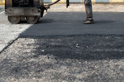 Low section of man pouring hot asphalt