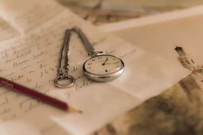 High angle view of pocket watch and pencil on letter