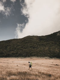 Man riding on field against sky