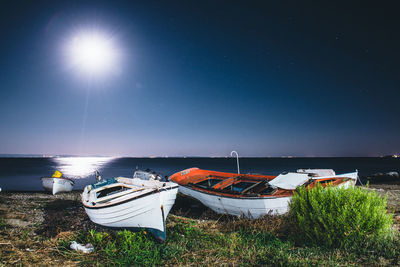 Boat moored on beach against sky at night