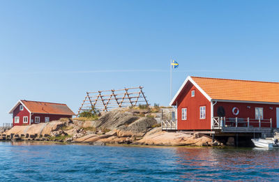 Houses by sea against clear sky