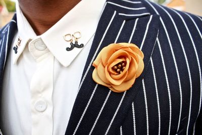 Midsection of man with artificial flower on blazer