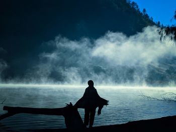 Rear view of silhouette woman looking at lake against sky