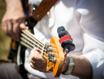 Midsection of man playing guitar outdoors