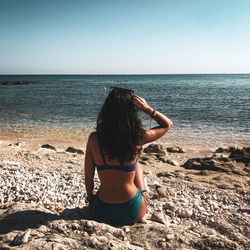 Rear view of woman at beach against clear sky