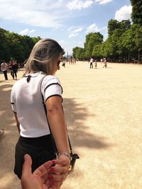 Cropped image of man holding woman hand in park