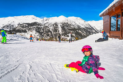 A child, sitting on the ski slope, smiling and looking at camera, andorra