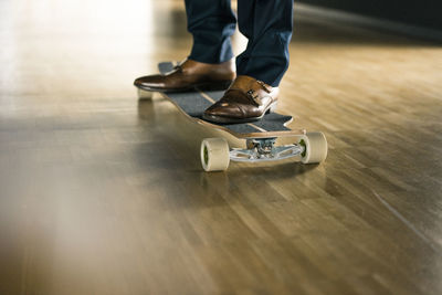 Businessman riding longboard on wooden floor