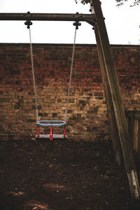 Empty swing in playground against sky