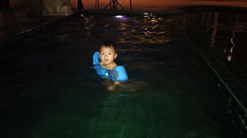 Boy swimming in water at night