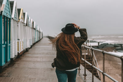 Rear view of woman photographing by railing against sky