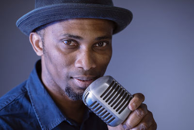 Portrait of man holding microphone standing in recording studio