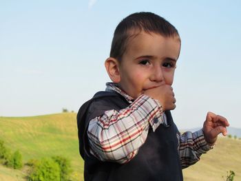 Portrait of smiling boy on field against sky