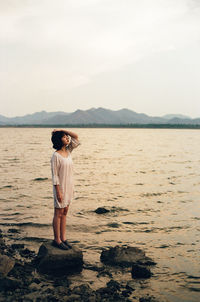 Full length of woman standing on beach against sky