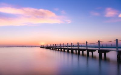 Pier over sea against sky during sunset