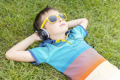 Portrait of young woman wearing sunglasses while sitting on grassy field