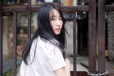 Portrait of young woman standing by gate