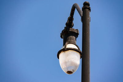 Low angle view of light bulb against clear blue sky