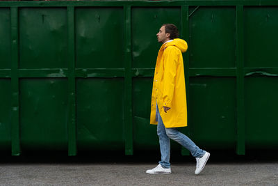 Side view of man wearing raincoat walking on road