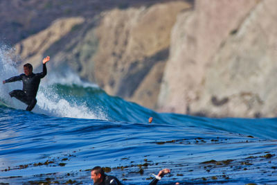 Man surfing on rock in sea