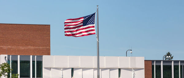 Low angle view of flag against building against clear sky