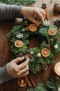 Top view of the hands of a male florist making a christmas wreath from natural materials. decoration
