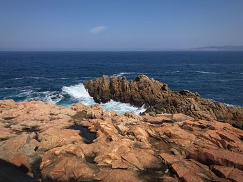 Rock formations on shore against blue sky