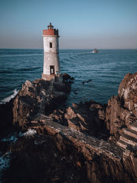 Lighthouse by sea against sky