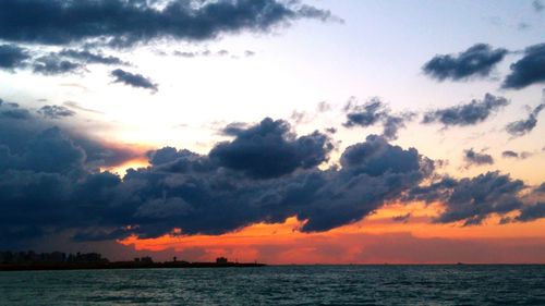 Scenic view of sea against cloudy sky during sunset