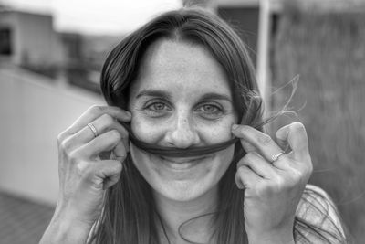 Portrait of woman making mustache with her hair