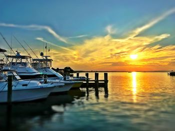 Boats moored at harbor against sky during sunset