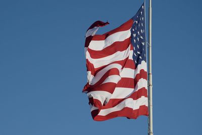 Low angle view of american flag against clear blue sky