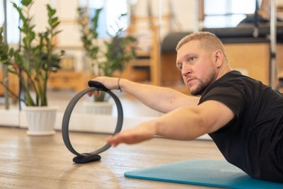 Male fitness pilates trainer shows exercises on special simulators. rubber rings for stretching