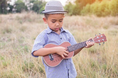 Boy playing guitar on field