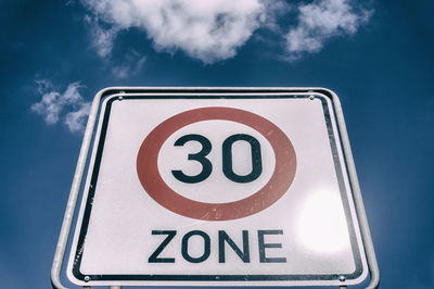 Low angle view of speed limit sign against blue sky during sunny day