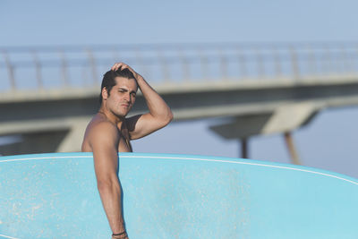 Shirtless man with surfboard at beach