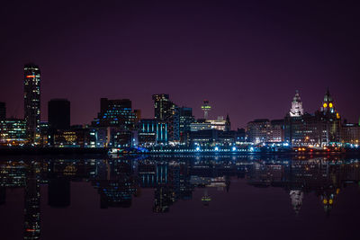 Reflection of illuminated city on calm lake at night