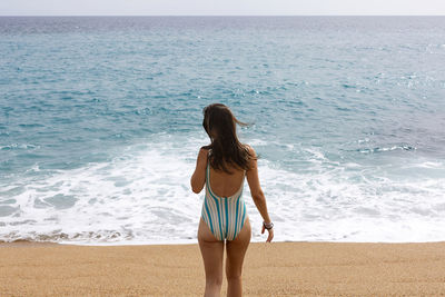 Rear view of woman standing at beach