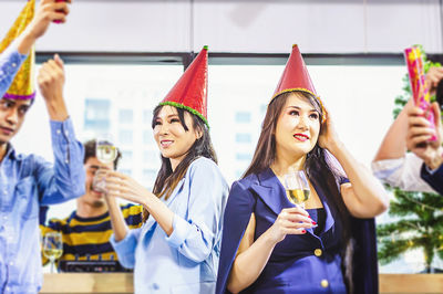 Cheerful colleagues wearing party hat celebrating in office