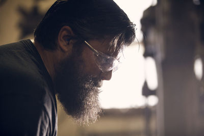 Close-up of blacksmith wearing protective eyewear working in workshop