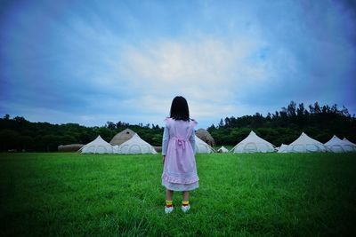 Rear view of woman standing on field against sky